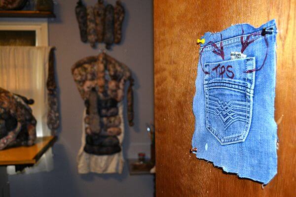 A cut out back jean pocket with the word "tips" written on it, pinned to a door