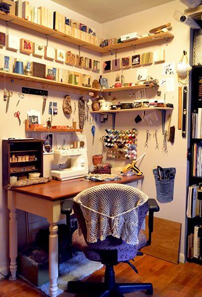 A fiber artist's studio desk with spools of thread and a sewing machine