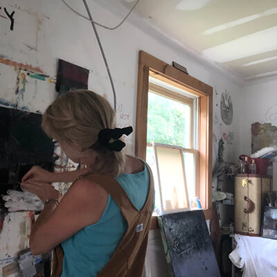 A painter works on a work on canvas in her studio