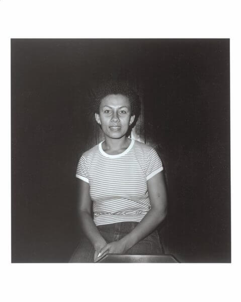 A black and white photograph of a woman sitting in a striped t-shirt