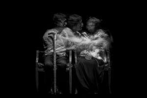 A black and white photograph of stacked images of a man in a chair