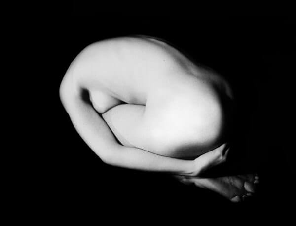 Black and white photograph of a naked woman in a kneeling position