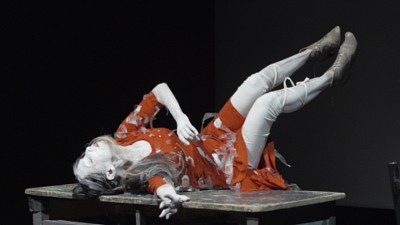 A performance artist in a pose on top of a table