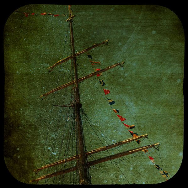 Edited photograph of the mast of a sailboat among a dark background