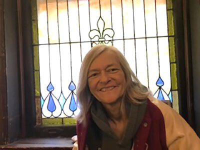 Headshot of poet Pamela Sumners with a stained glass window in the background