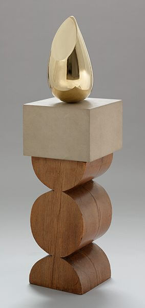 A golden sculpture on a pedestal of limestone and wood