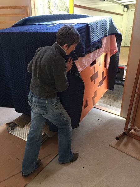 An artist moves her pieces on a rolling crate into a new studio