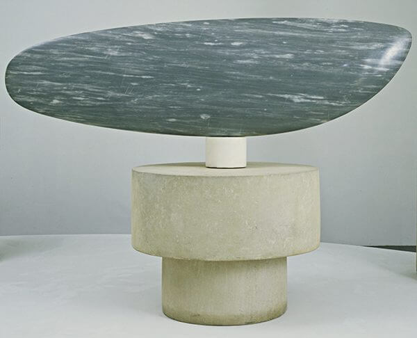 A wide blue-gray marble sculpture on a pedestal of white marble and limestone