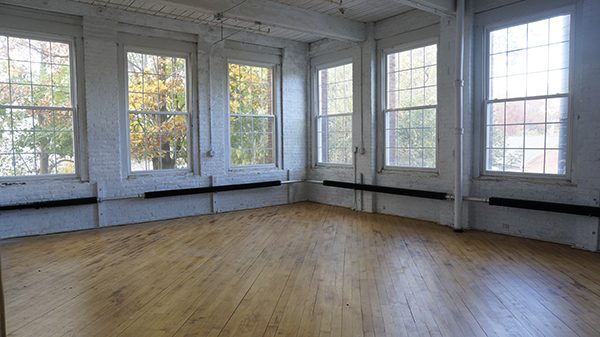 An empty artist's warehouse studio, with wood floors and high-ceiling windows