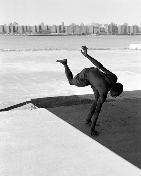 Black and white photograph of a man balancing on one leg