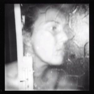 Black and white photograph of a woman against a shower door