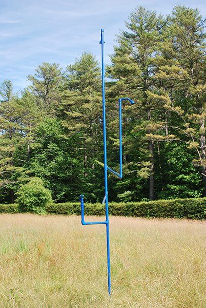 A bright blue water faucet in the middle of a field of grass