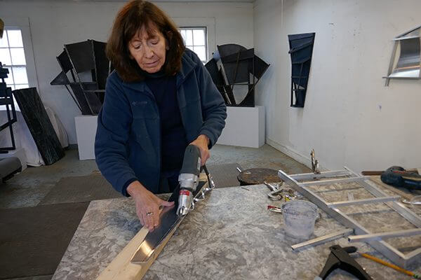 An artist working on aluminum sculpture with hand tools