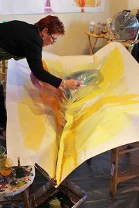 Bette Ridgeway in her studio demonstrating her pouring technique.