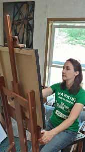 Maya Kuvaja painting at an easel in her studio