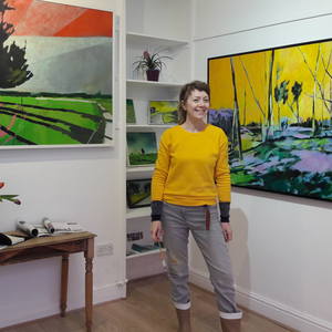 Painter Ruth Bunnewell in front of her colorful landscapes