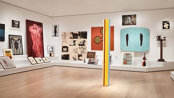 Installation view of sculptures, drawings, and paintings on the wall and lining shelves of a gallery