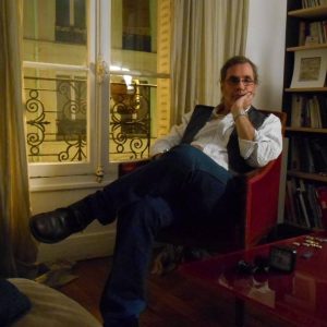 Photographer John Greiner Ferris sits in front of a bookshelf