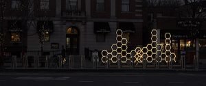 An installation of lit honeycomb-like shapes on a city sidewalk