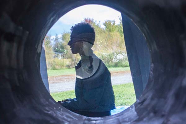 A winidow looking in to a person sitting inside of an art installation in a park