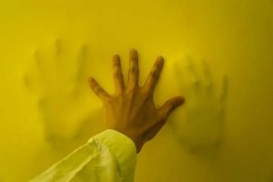 A hand presses against a nylon yellow sheet as part of an interactive art installation