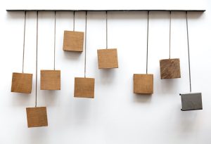 A sculpture of wooden blocks hanging from a stand on different lengths of wire