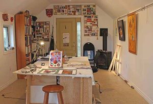 A worktable lined with paintings and the entrance to an artist's studio