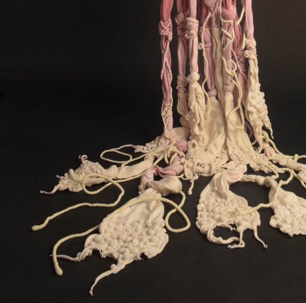 Long, thick pieces of red to white ombre fiber hang from the ceiling as an art installation