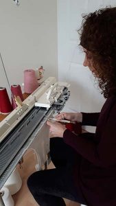 Tara Kennedy knits at a machine in her parent’s home.