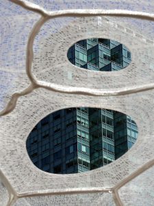 A photograph of a skyscraper behind two holes in another building