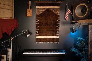 A keyboard with fabric wall art and guitars hung on the wall above