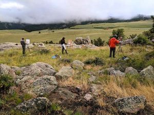 A group of people painting on a high grassy plateau