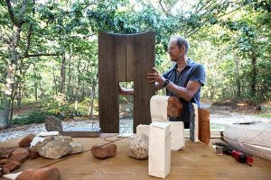 Mark Webber works on a wood sculpture outside his studio