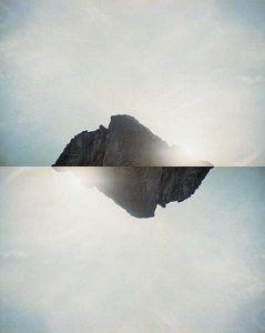 A photocollage of a mountain reflected against itself