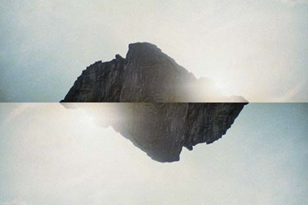 A photocollage of a mountain reflected against itself