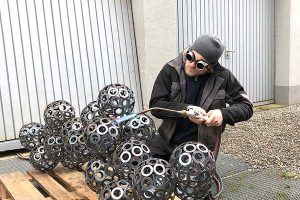 An artist uses a torch to work on a metal sculpture outside