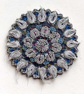 A blue, white, and red orb-shaped piece of artwork made from tightly wound pieces of paper.