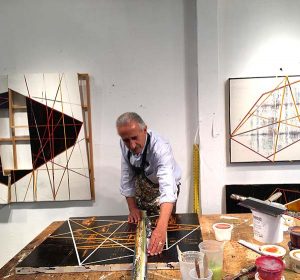 A painter uses a ruler to draw lines on a work in progress in his studio